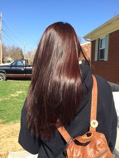 a woman with long hair carrying a brown purse