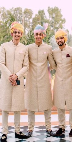 three men wearing turbans standing next to each other on a checkered floor