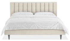 a bed with white linens and pillows on top of the headboard is shown