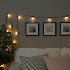 three framed pictures hang on the wall above a white couch with pillows and throw pillows