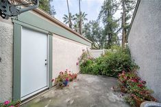 an outside view of a house with flowers and plants in the front yard, next to a door