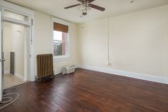 an empty room with hard wood flooring and a fan on the wall in it