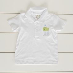 a white polo shirt with a green frog on the front and blue letters on the back