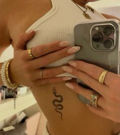 a woman is holding her cell phone up to her stomach and showing off her tattoos