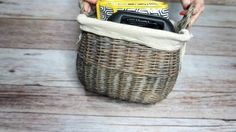 a person holding a cell phone in a wicker basket on a wooden floor with wood planks