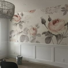 an empty room with flowers painted on the wall and a birdcage hanging from the ceiling