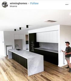 a man is standing in the middle of a room with white cabinets and black countertops