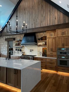 a large kitchen with wooden cabinets and an island in the middle is lit by lights