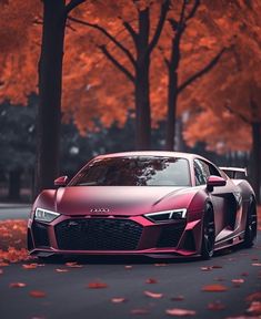 a pink car parked on the side of a road next to trees with orange leaves