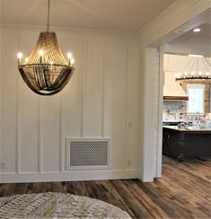 a chandelier hanging from the ceiling in a room with hard wood flooring