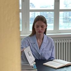 a woman sitting at a table with an open book in front of her and looking down