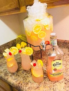 several glasses filled with drinks sitting on top of a counter next to bottles and lemons