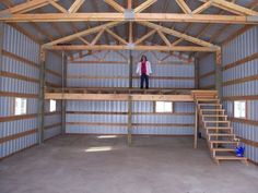 a woman standing on top of a wooden platform in a large room with metal walls