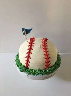 a baseball cake with green grass and red stitches on the top, topped with an american flag