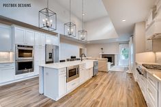 a large kitchen with white cabinets and wood flooring is pictured in this image, there are lights hanging from the ceiling