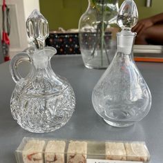 two glass vases sitting on top of a table next to some candy cubes