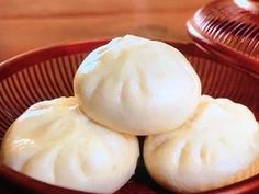 three dumplings in a red bowl on a wooden table