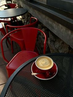 a cup of coffee sitting on top of a saucer next to a red chair