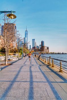 people are walking on the sidewalk by the water