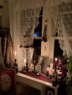 a table with candles and pictures on it in front of a window filled with curtains