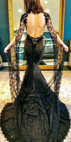 the back of a woman's dress in front of a mirror with her hands on her hips