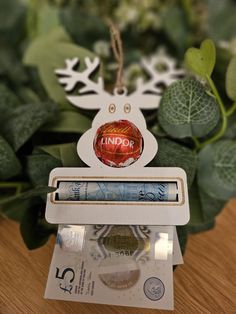 a christmas ornament on top of money with greenery in the back ground