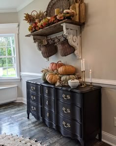 a black dresser topped with lots of pumpkins and gourmet dishes sitting on top of it