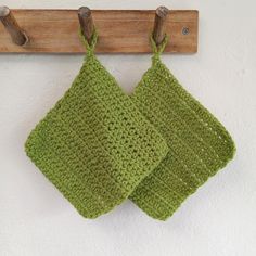 two green crocheted dishcloths hanging from a wooden hook