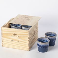 three cups in a wooden box and one empty cup on the side, sitting next to each other