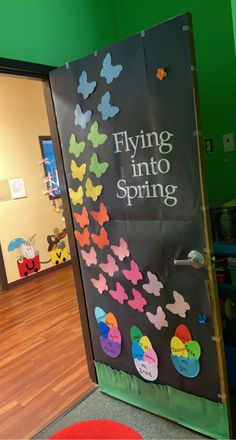 a classroom door decorated with butterflies and the words flying into spring