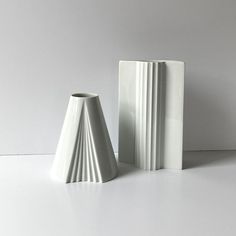 two white vases sitting next to each other on a table