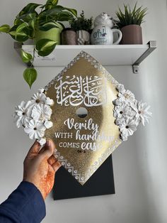 someone holding up a gold graduation cap with white flowers