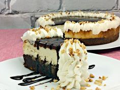 two slices of cheesecake on plates with chocolate sauce and whipped cream