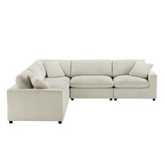 a white sectional couch with pillows on the back and armrests, sitting in front of a white background