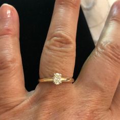 a close up of a person's hand with a diamond ring on their finger