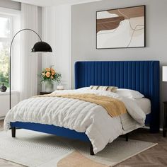 a bed with blue headboard and white sheets in a bedroom next to a window