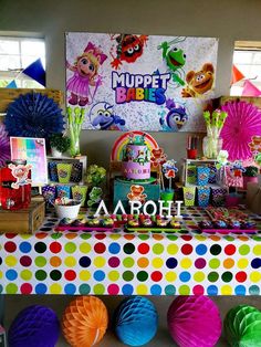 there is a colorful table with lots of decorations on it and balloons in the background