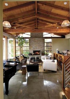 a living room filled with furniture and a piano in front of a fire place on top of a hard wood floor