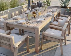 an outdoor dining table set up with white plates and place settings for six on a patio