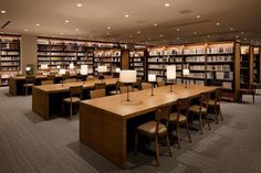 an empty library filled with lots of books and desks next to lamps on either side of the tables