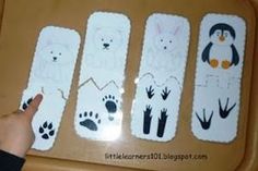 a child's hand is pointing at four animal bookmarks on a table with their fingers