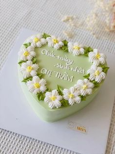 a green heart shaped cake with daisies on the top and writing in white lettering