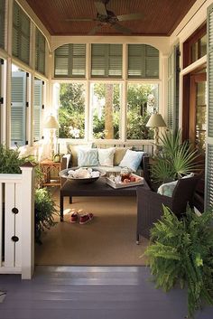 an enclosed porch with couches and potted plants