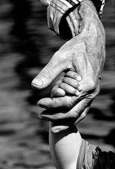 two hands holding each other in front of water