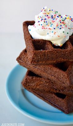 chocolate waffles topped with whipped cream and sprinkles on a blue plate