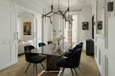 an elegant dining room with white walls and wood flooring is furnished with black chairs