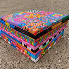 four brightly colored boxes are stacked on top of each other in the middle of sand