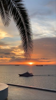 the sun is setting over the ocean and boats are in the water behind it,