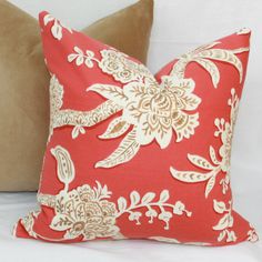 two red and white pillows sitting on top of a bed next to each other in front of a brown pillow