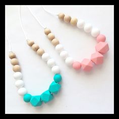 two necklaces with wooden beads and white, pink, and blue shapes on them